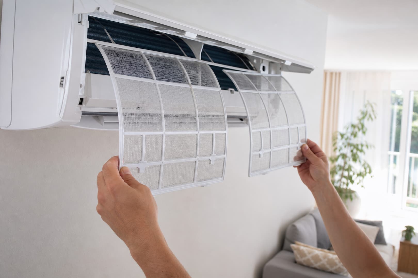 Homeowner safely cleaning reusable filters from a ductless mini-split indoor unit