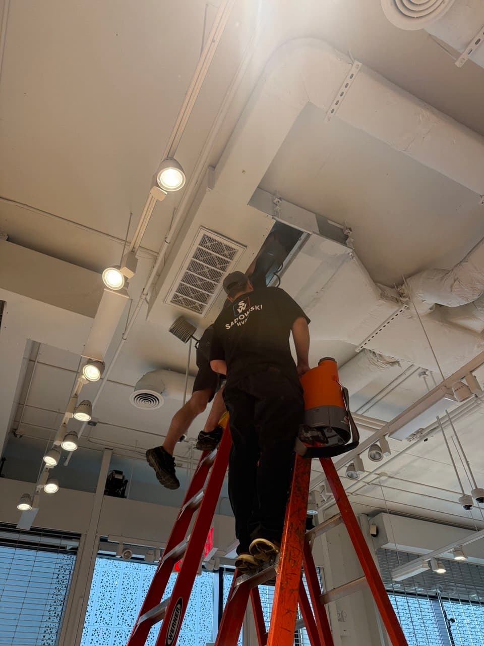 Sadowski HVAC technician servicing a ceiling-mounted commercial indoor unit